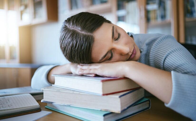 Sleeping, tired and fatigue student with books studying for university exam, learning and knowledge